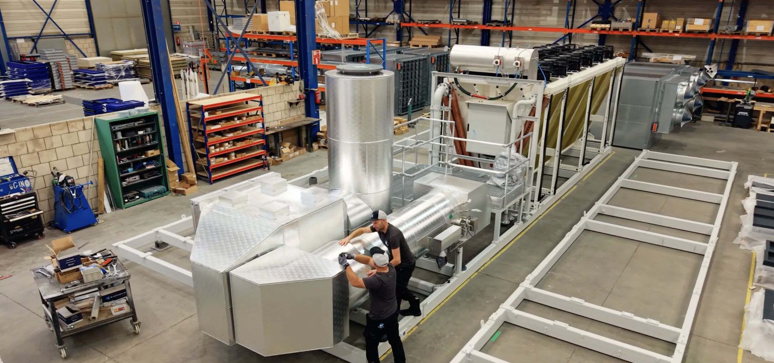 Twee medewerkers van AX Isolatiewerken werken aan de aluminium ommanteling van een installatie in de werkplaats