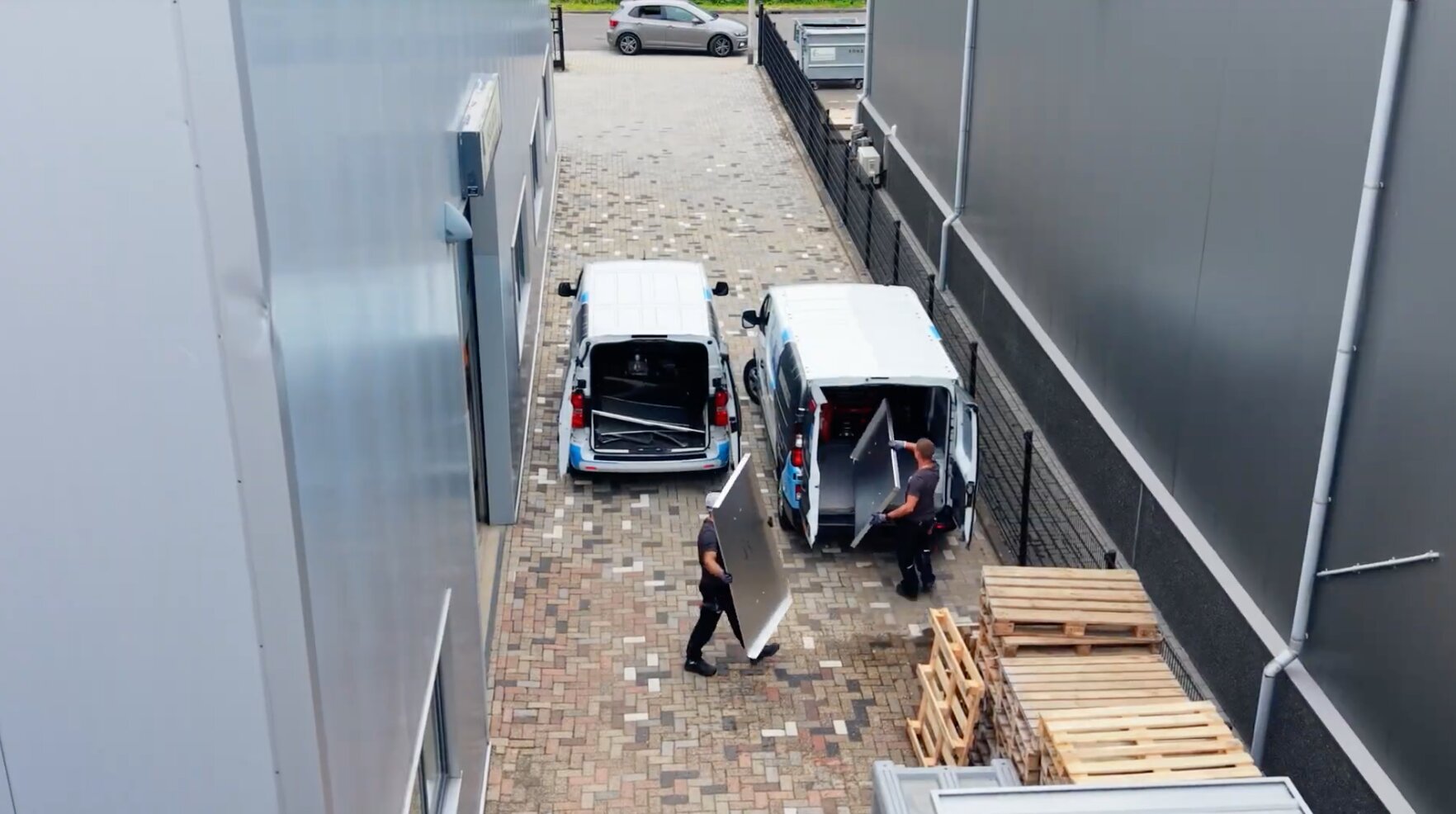 Twee medewerkers van AX Isolatiewerken laden plaatwerk in bedrijfsbussen naast het bedrijfspand